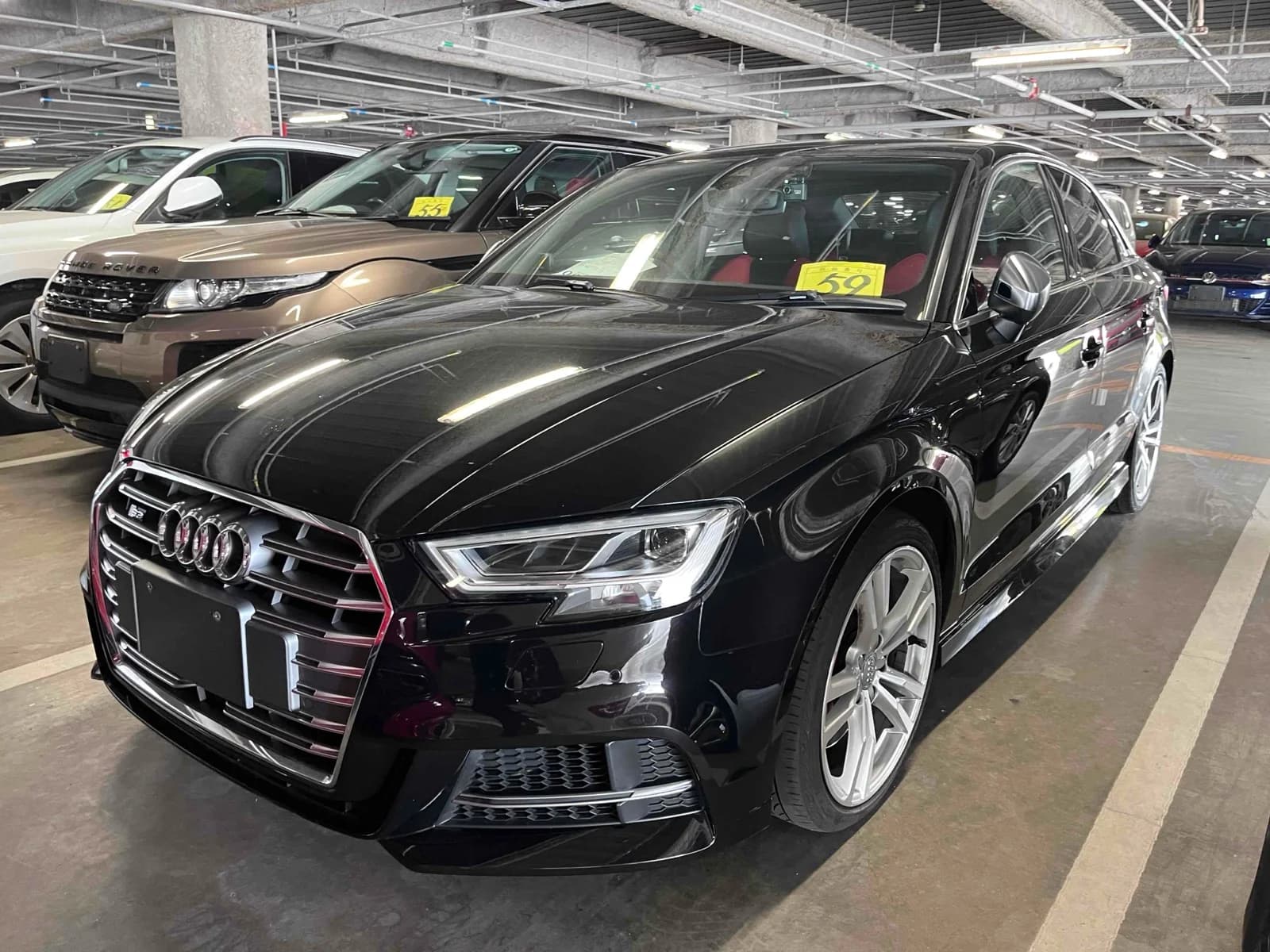 Front three-quarter view of a black Audi S3 sedan parked in a covered auction lot