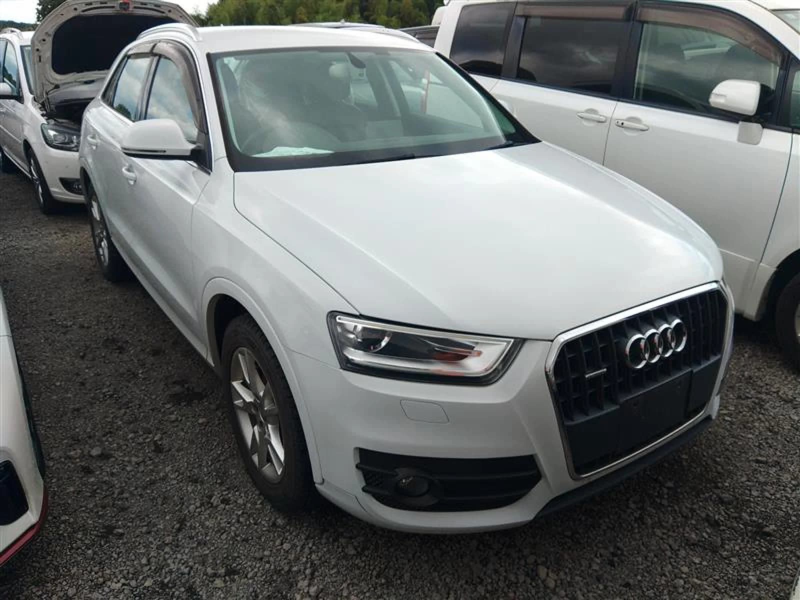 Front three-quarter view of a white Audi Q3 SUV parked in a gravel auction lot