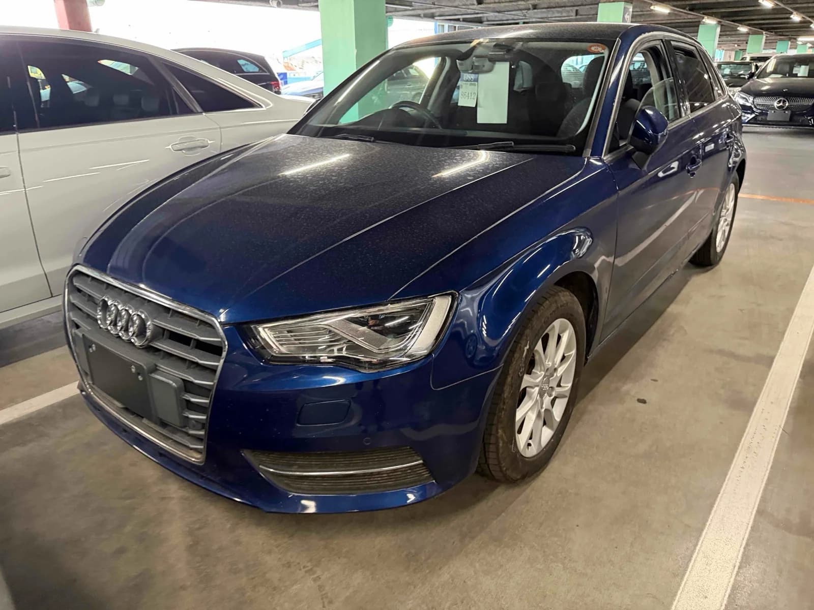 Front three-quarter view of a blue Audi A3 Sportback parked in a covered auction garage