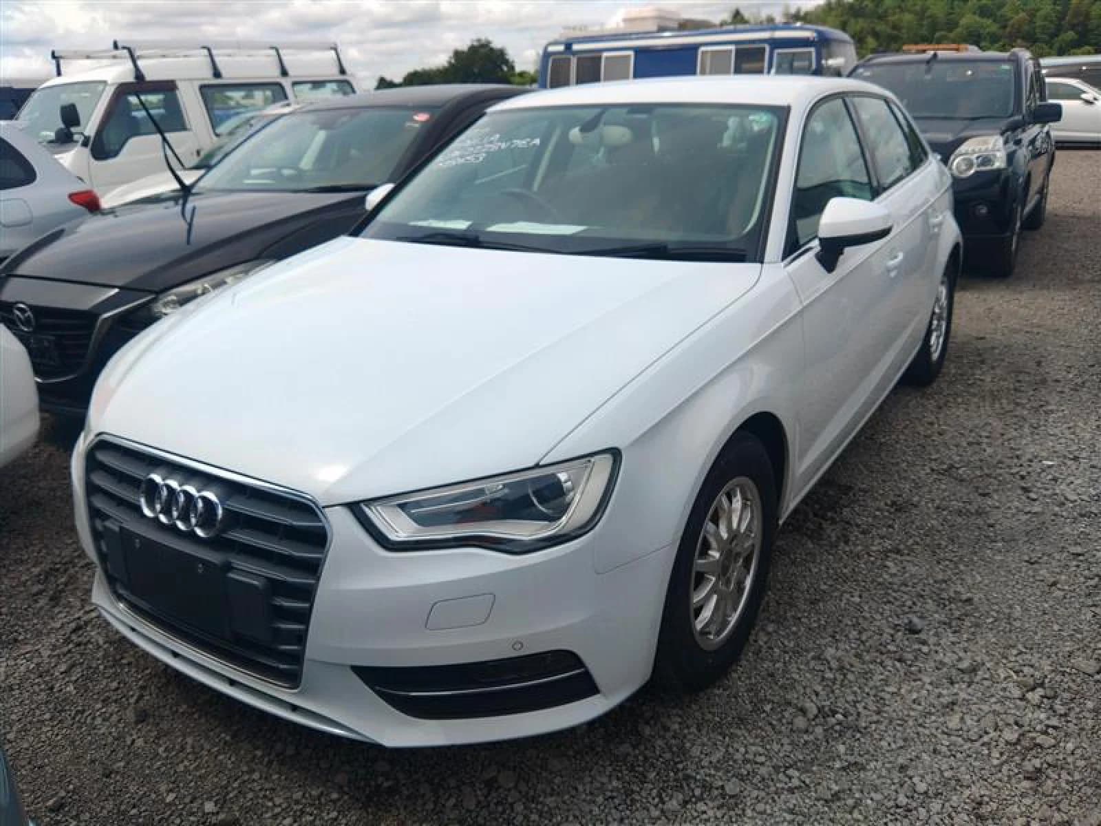 Front three-quarter view of a white Audi A3 sedan parked in a gravel auction lot