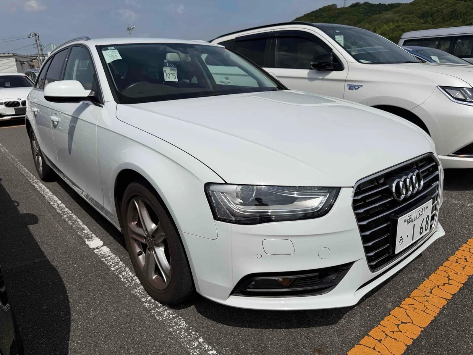 Front three-quarter view of a white Audi A4 Avant wagon parked outdoors in an auction lot