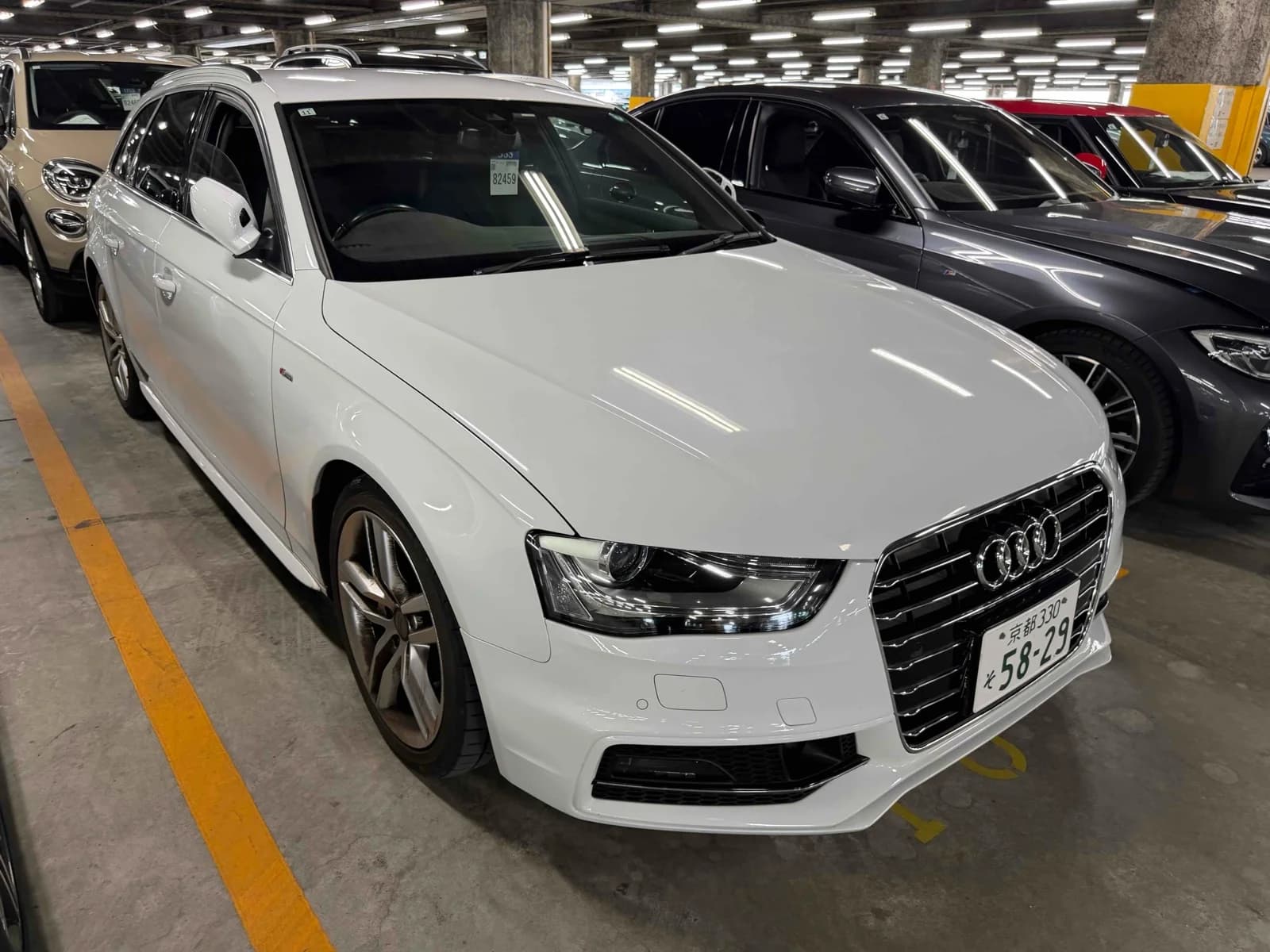 Front three-quarter view of a white Audi A4 Avant S line wagon parked in a multi-level auction lot