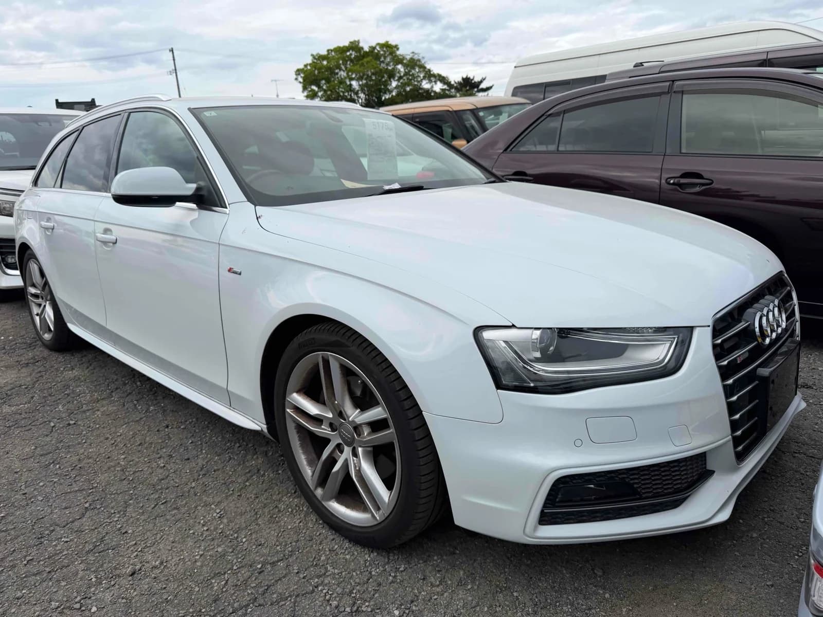 Front three-quarter view of a white Audi A4 Avant S line wagon parked in an auction lot