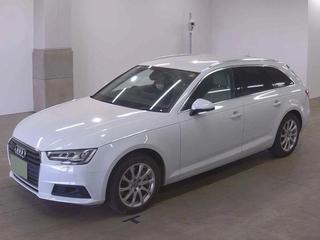 Front three-quarter view of a white Audi A4 Avant wagon inside an auction inspection garage
