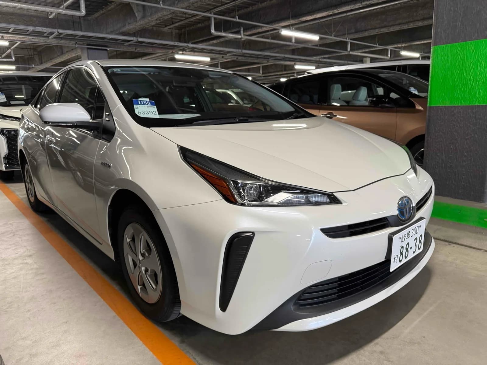2019 Toyota Prius S 4WD in pearl white - front-right 3/4 view with LED headlights, blue hybrid Toyota emblem, vertical air intakes, and wheel covers