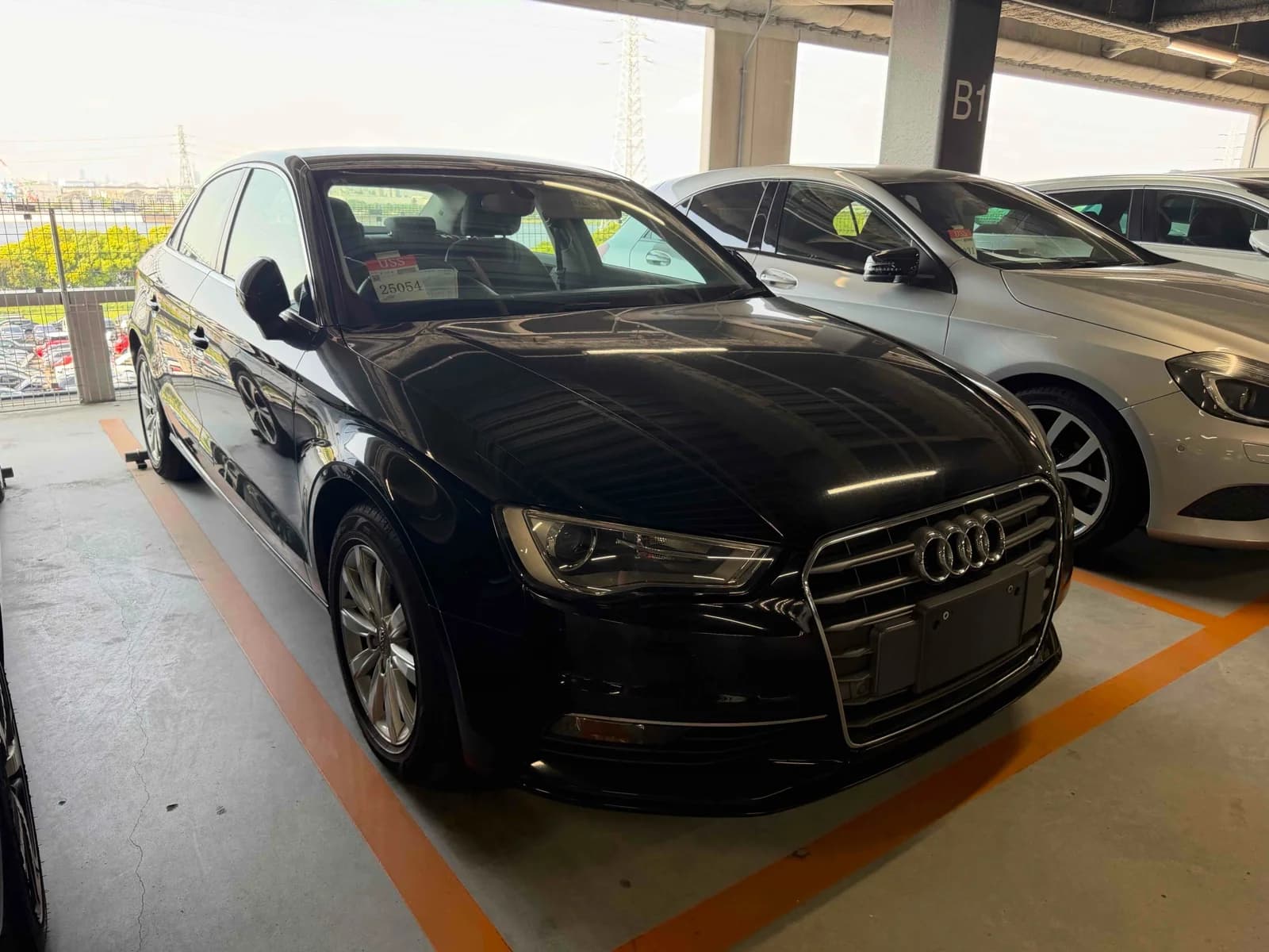 Front three-quarter view of a black Audi A3 sedan parked in a covered auction lot