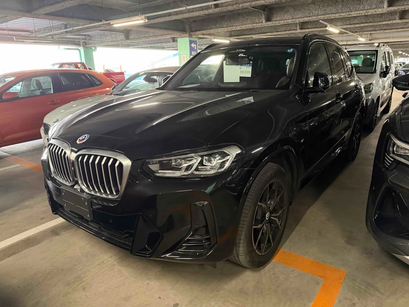 Front three-quarter view of a black BMW X3 SUV parked inside a multi-level auction garage