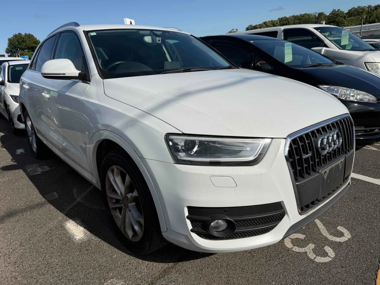 Front three-quarter view of a white Audi Q3 SUV parked in an outdoor auction lot