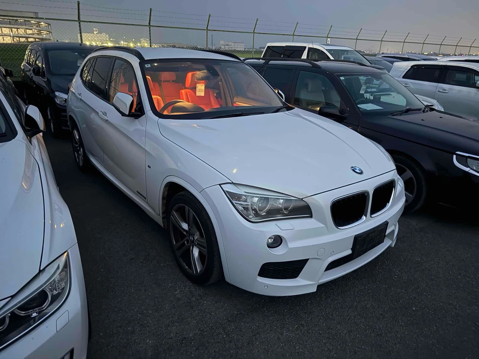 Front-left angle of white BMW X1 with orange interior