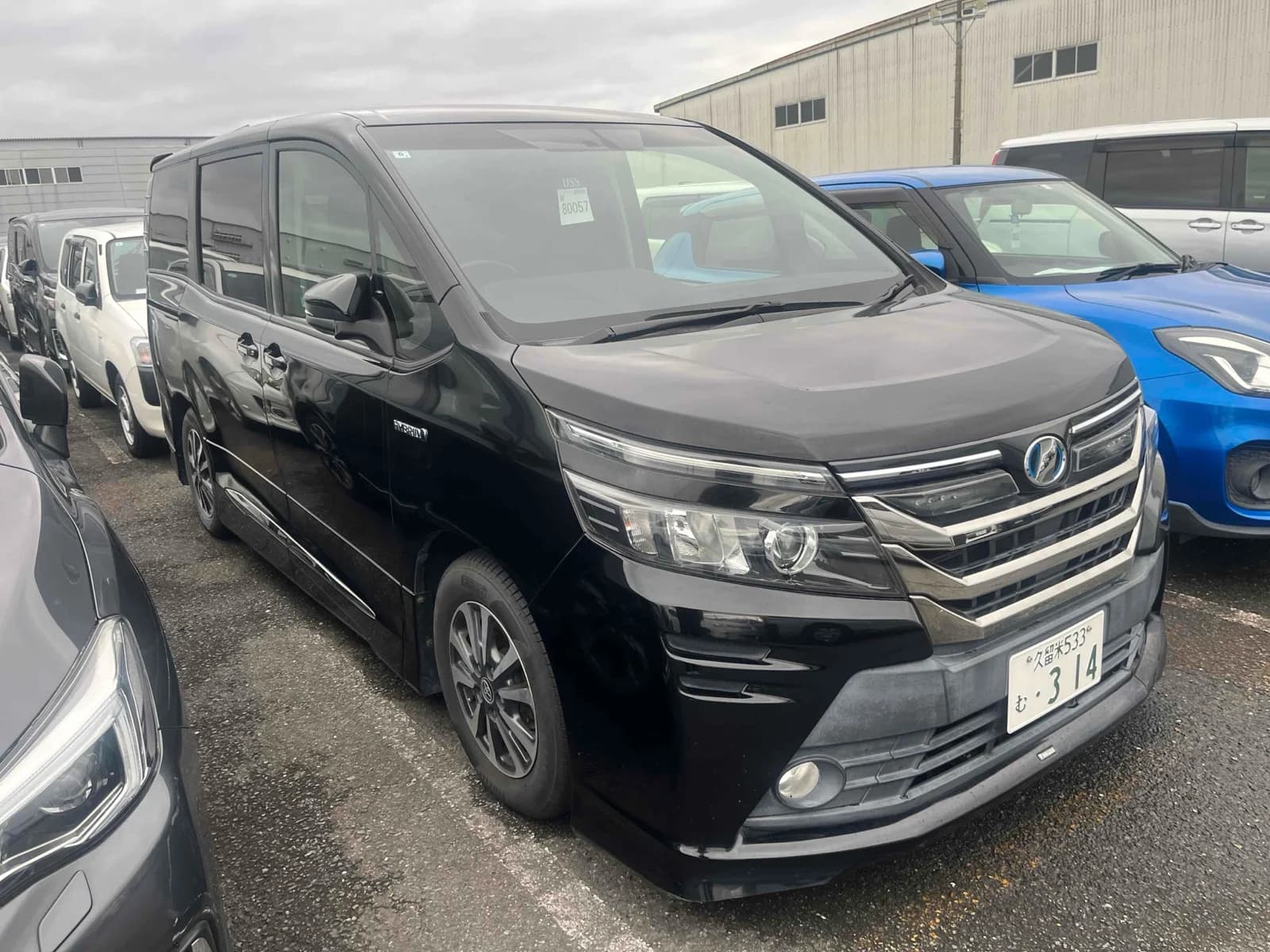 Toyota Alphard hybrid luxury minivan - Front-left 3/4 view with white pearl paint, LED headlights in warehouse