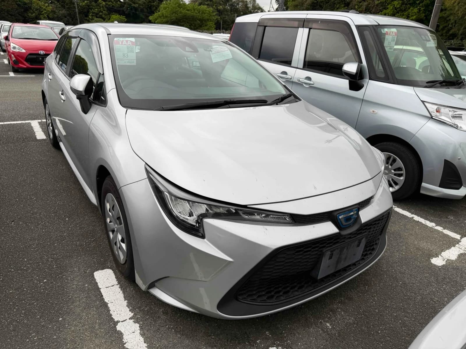 Toyota Corolla hatchback - Front-left 3/4 view showing white pearl paint, LED headlights, and modern compact design in parking lot