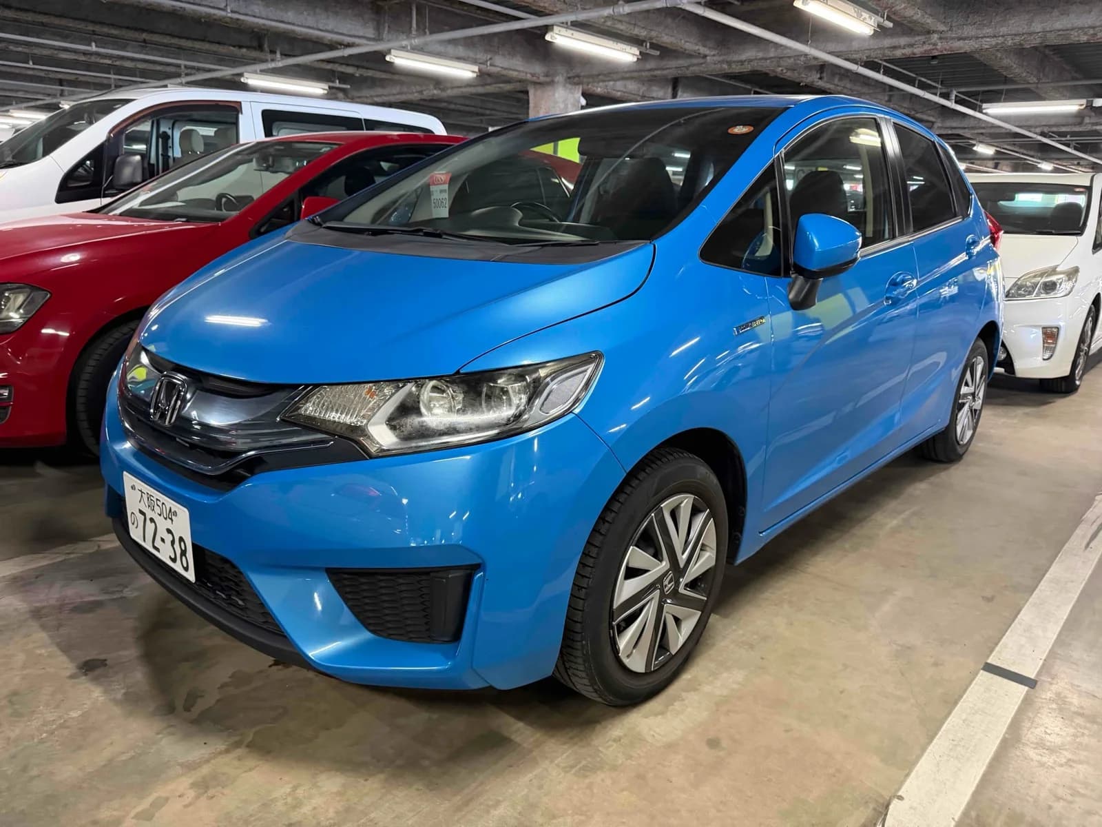 Honda Fit Hybrid - front-left 3/4 exterior view with vibrant blue paint and white alloy wheels