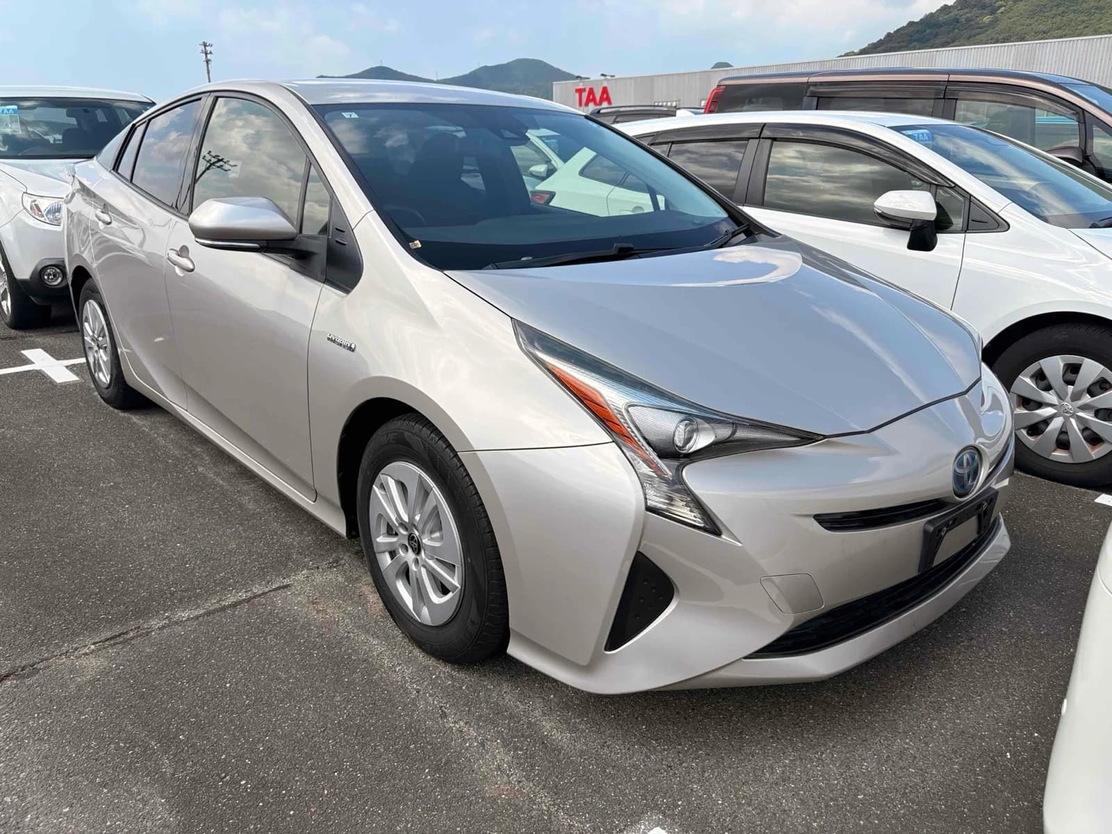Toyota Prius hybrid sedan - Front-left 3/4 view showing white pearl paint, LED headlights, modern design in auction lot