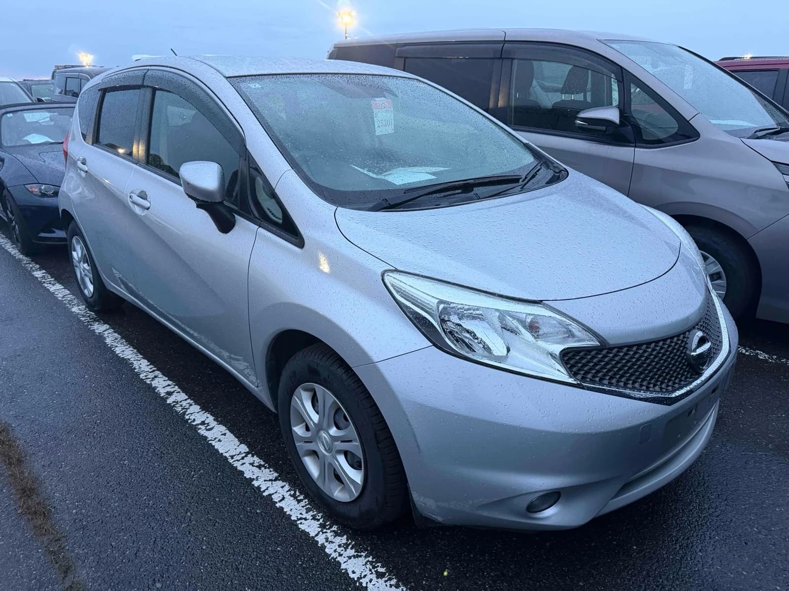 Pearl white Nissan Note compact hatchback - front-left 3/4 view showing distinctive grille and LED headlights