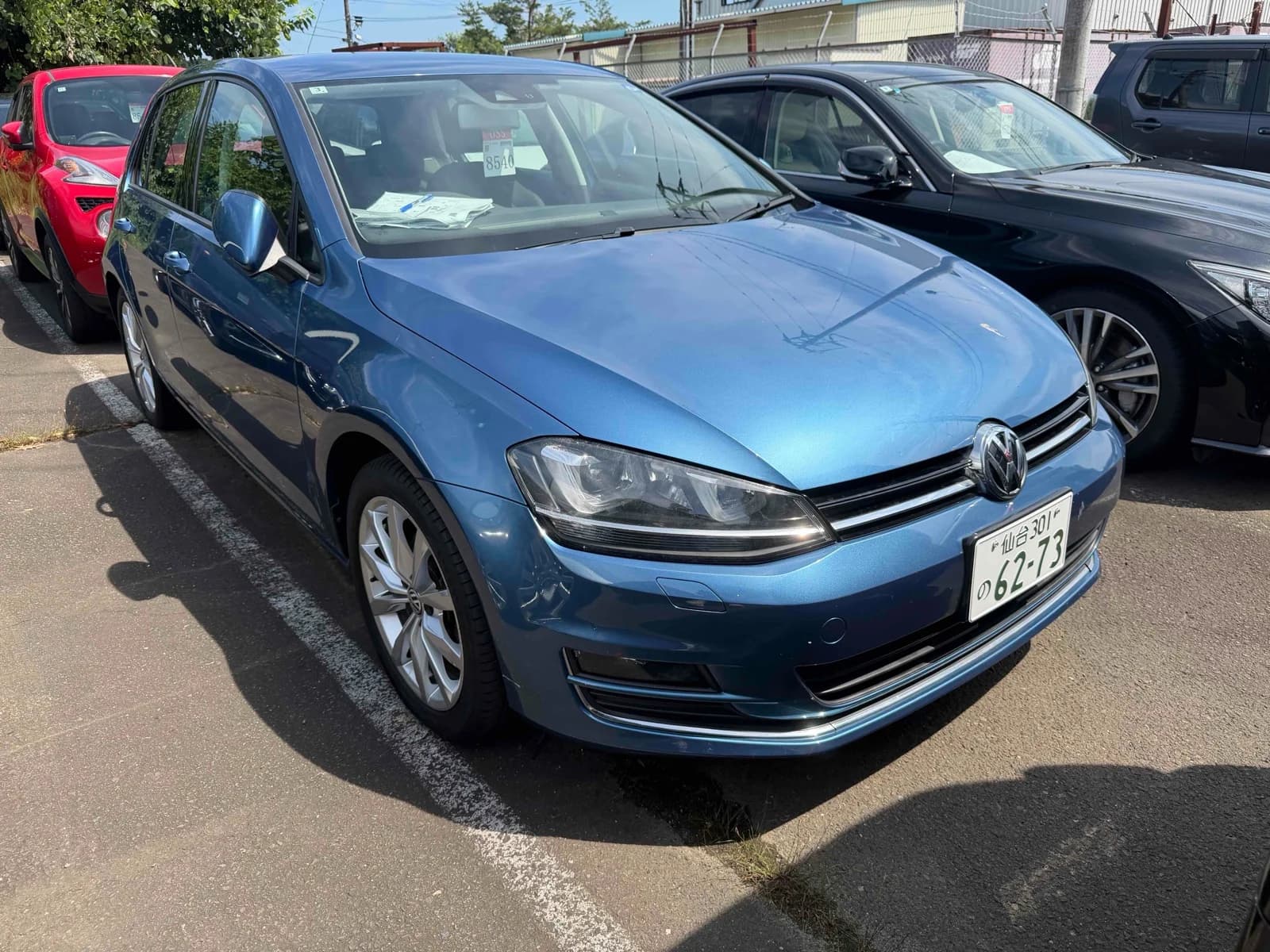 Volkswagen Golf 7.5 - Front-left 3/4 view showing blue metallic paint, LED headlights, chrome grille, and alloy wheels in parking lot