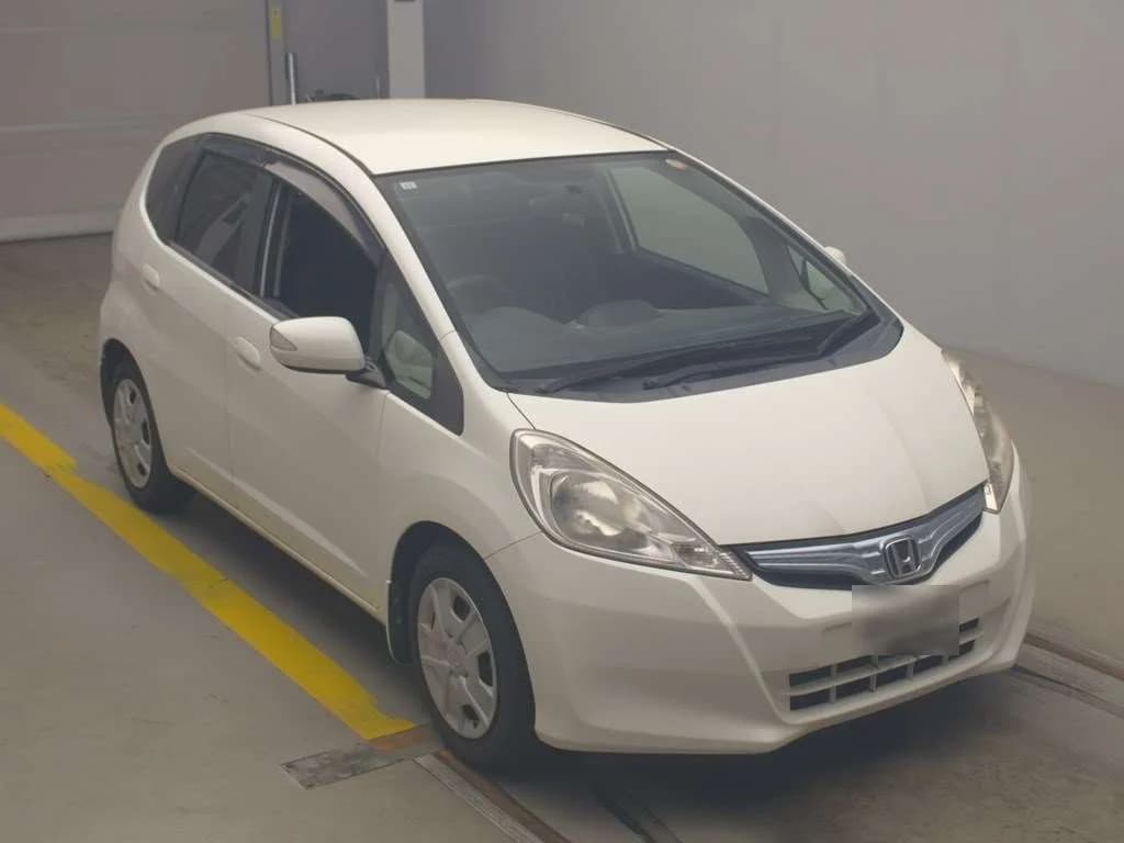 Pearl white Honda Fit compact hatchback - front-left 3/4 view inside covered garage facility
