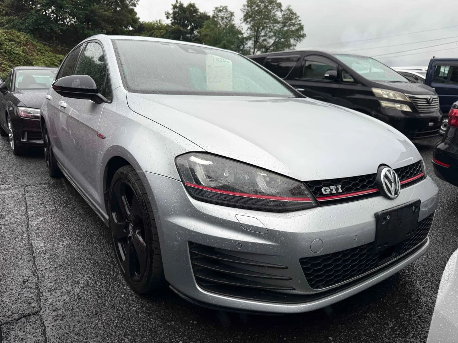 Volkswagen Golf GTI Mark 7 - Front-left 3/4 view showing pearl white paint, aggressive LED headlights, black grille with red stripe, and dark alloy wheels