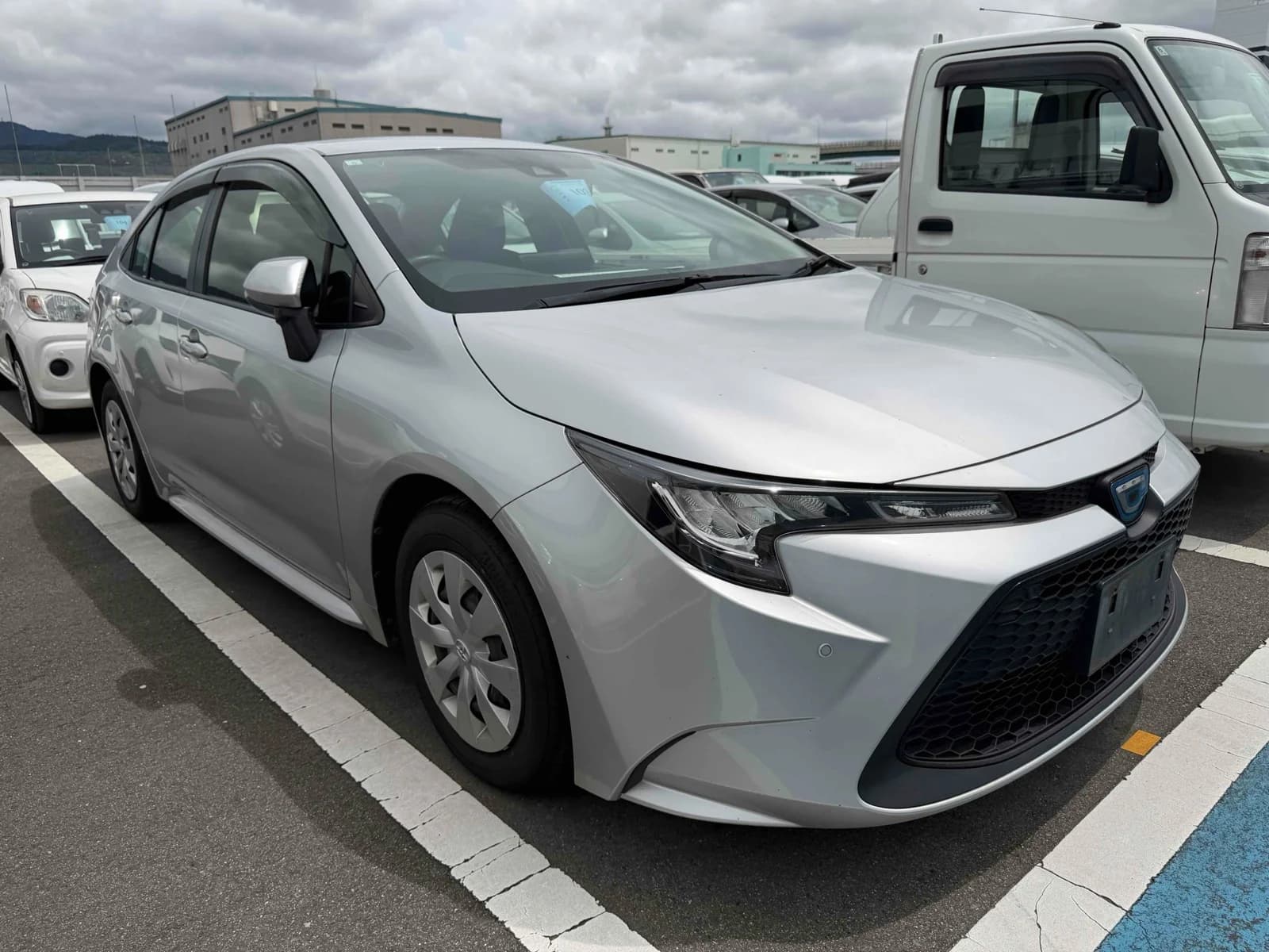 Silver Toyota Corolla sedan front-right three-quarter view at outdoor auction lot with LED headlights