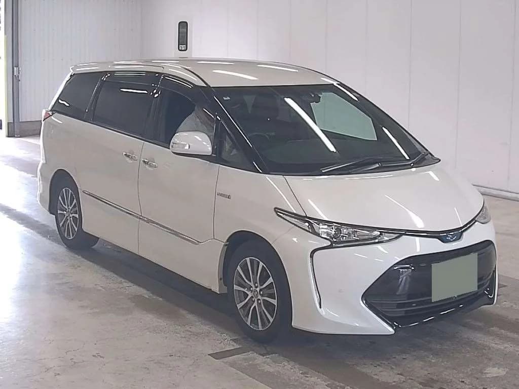 White Toyota Estima minivan front three-quarter view in warehouse setting