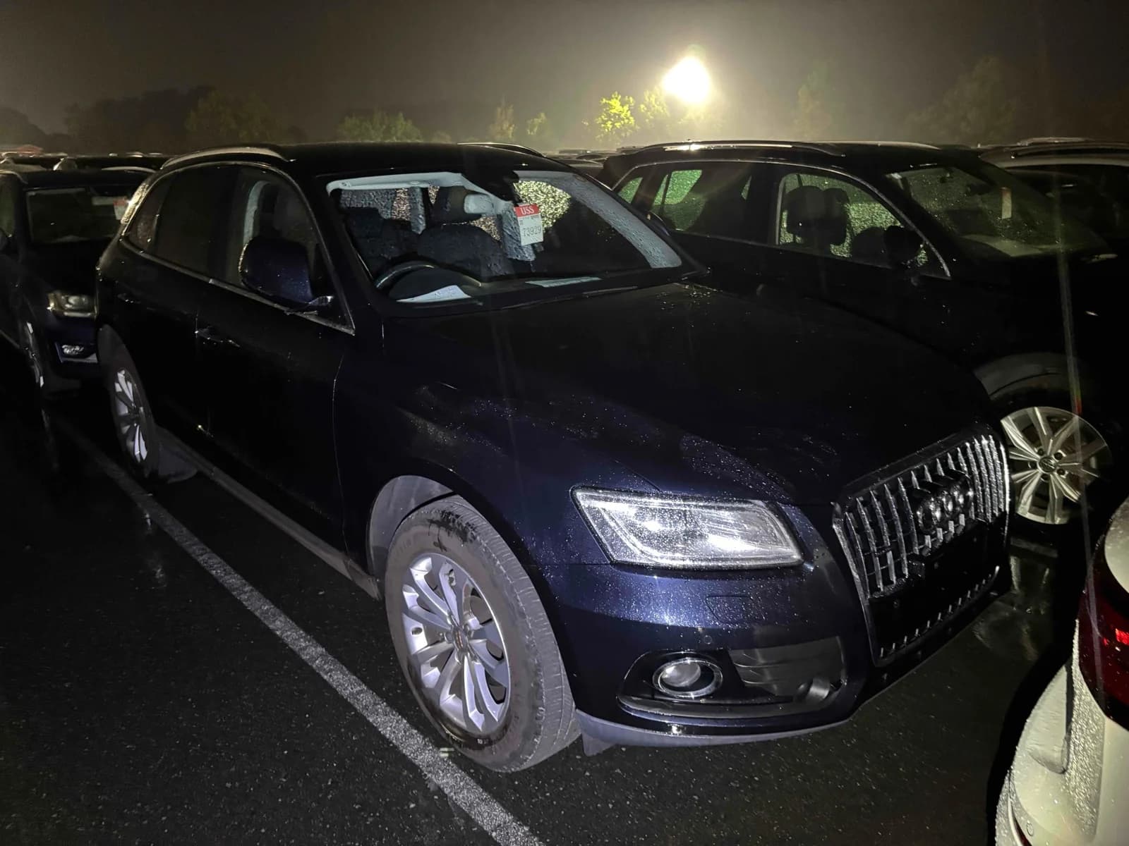 Dark blue Audi Q5 SUV front-right three-quarter night view at outdoor auction lot with chrome grille and LED headlights