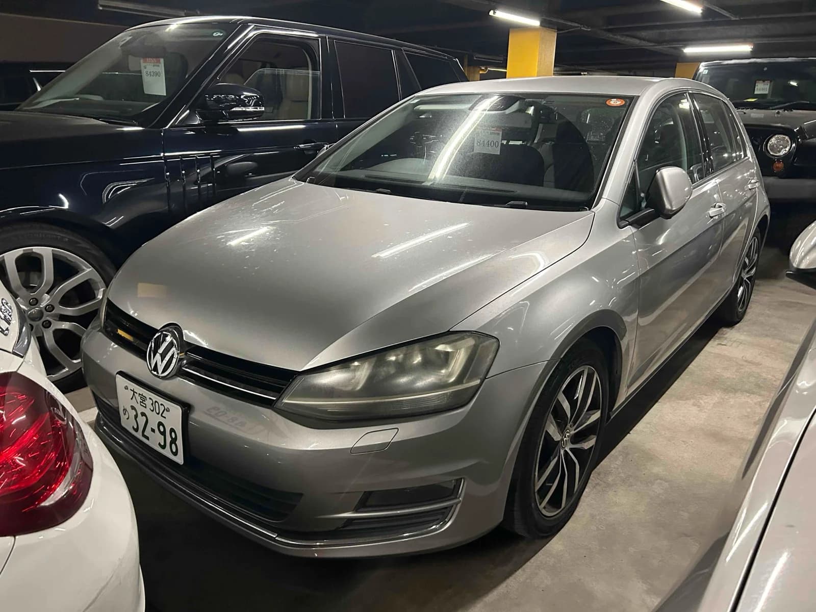 Silver Volkswagen Golf hatchback front-right three-quarter view in indoor parking garage with chrome grille