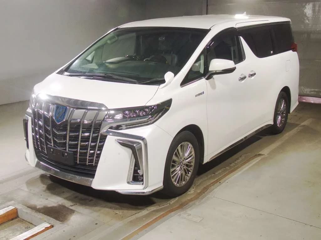 White Toyota Alphard minivan front three-quarter view in warehouse