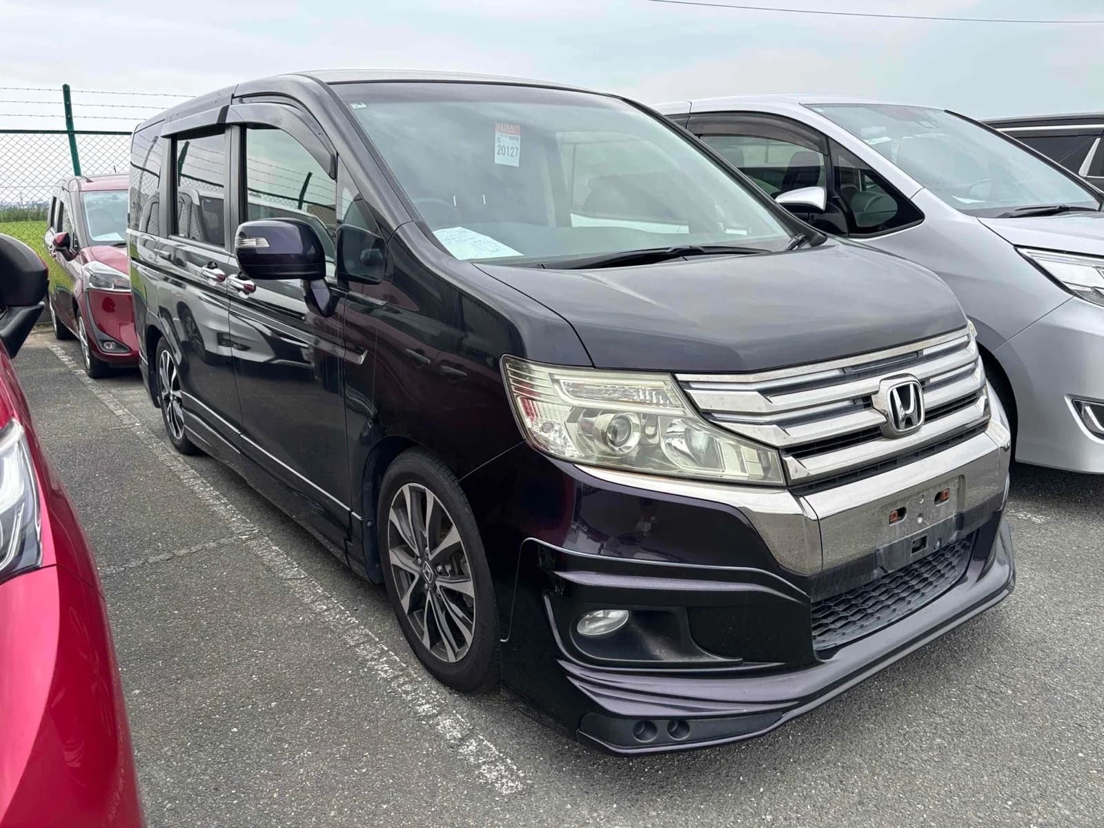 Black Honda Odyssey minivan front three-quarter view in auction lot with surrounding vehicles