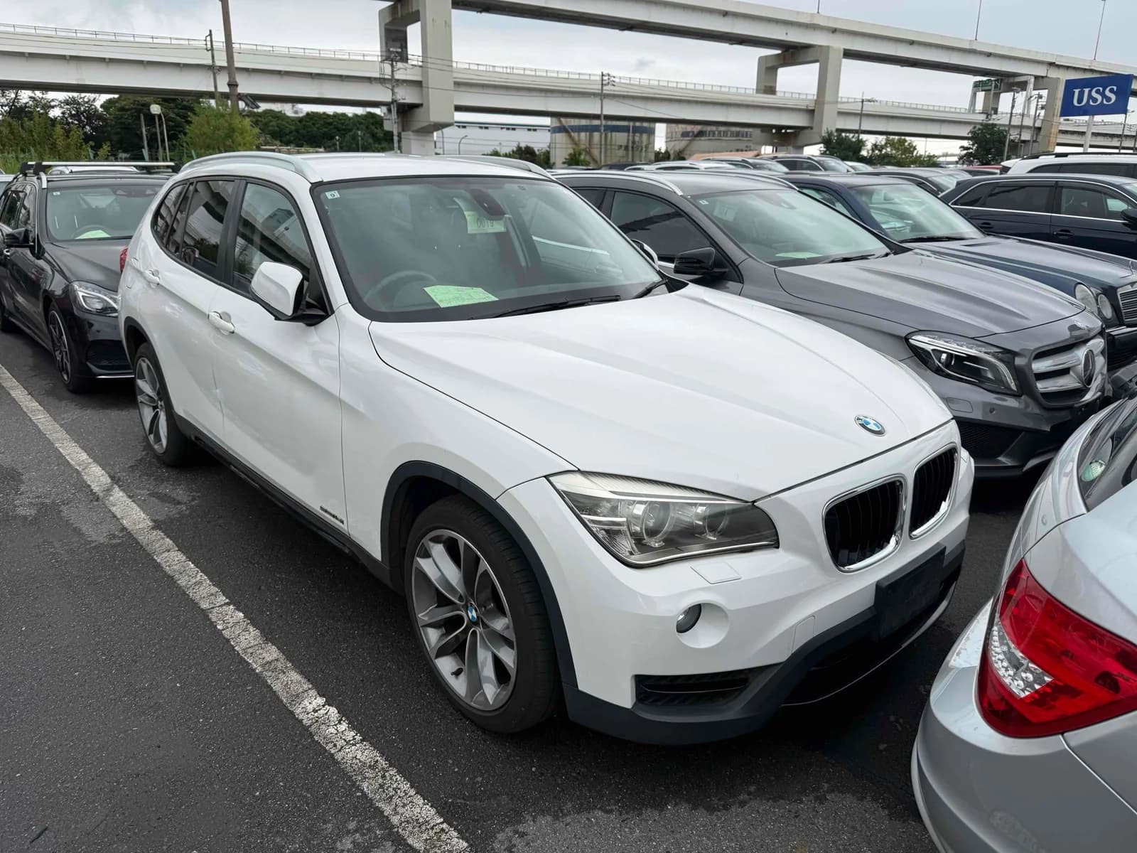 White BMW X1 SUV front-right three-quarter view at outdoor auction lot with chrome kidney grille and alloy wheels