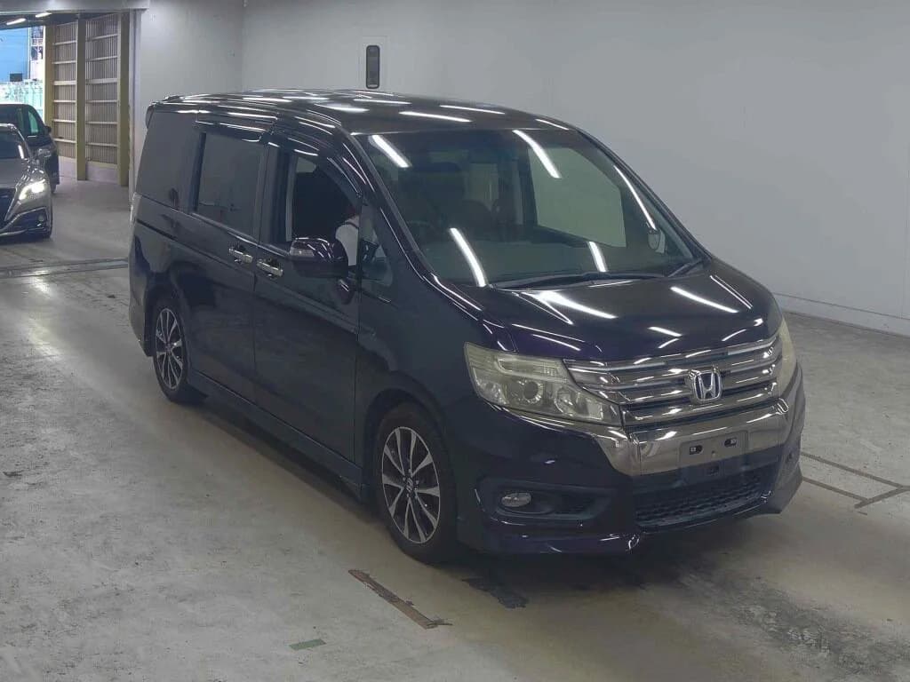 Dark purple Honda Odyssey Spada minivan front three-quarter view in garage warehouse
