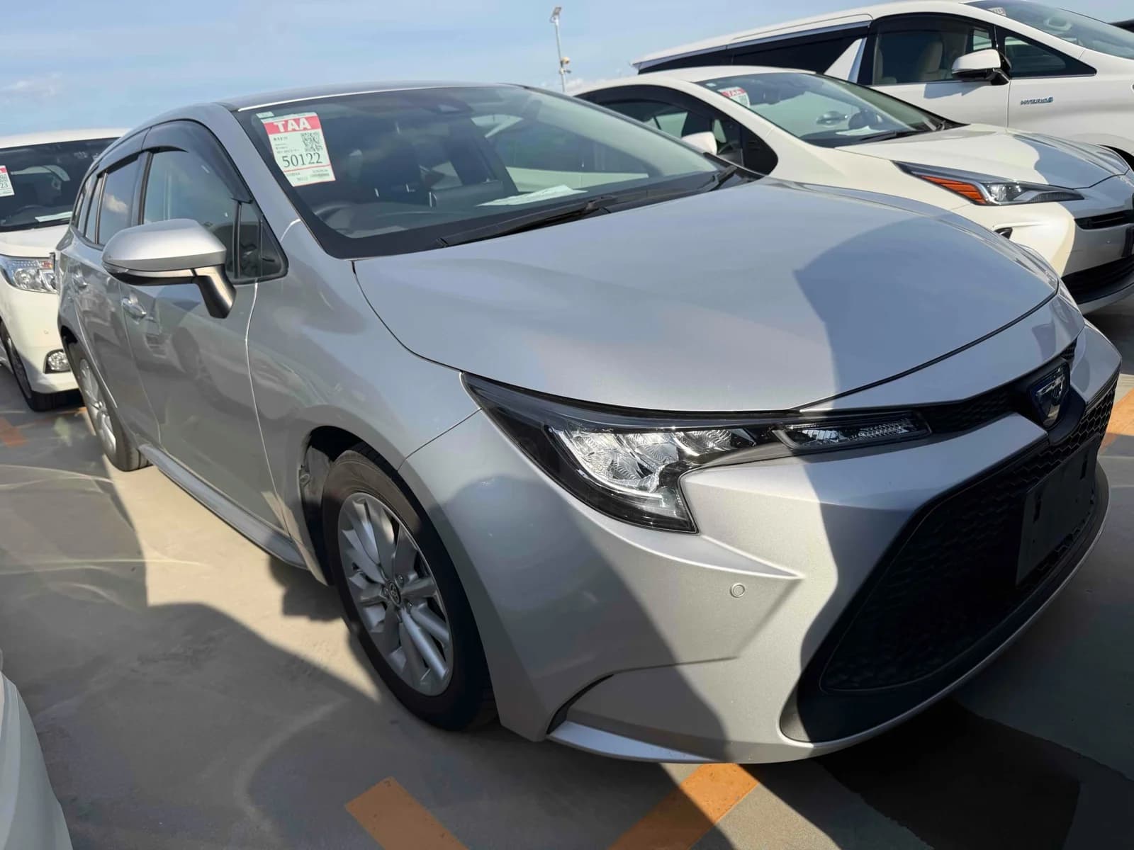 Toyota Corolla Touring wagon - Front-right exterior view in an outdoor auction lot with silver paint and Toyota emblem