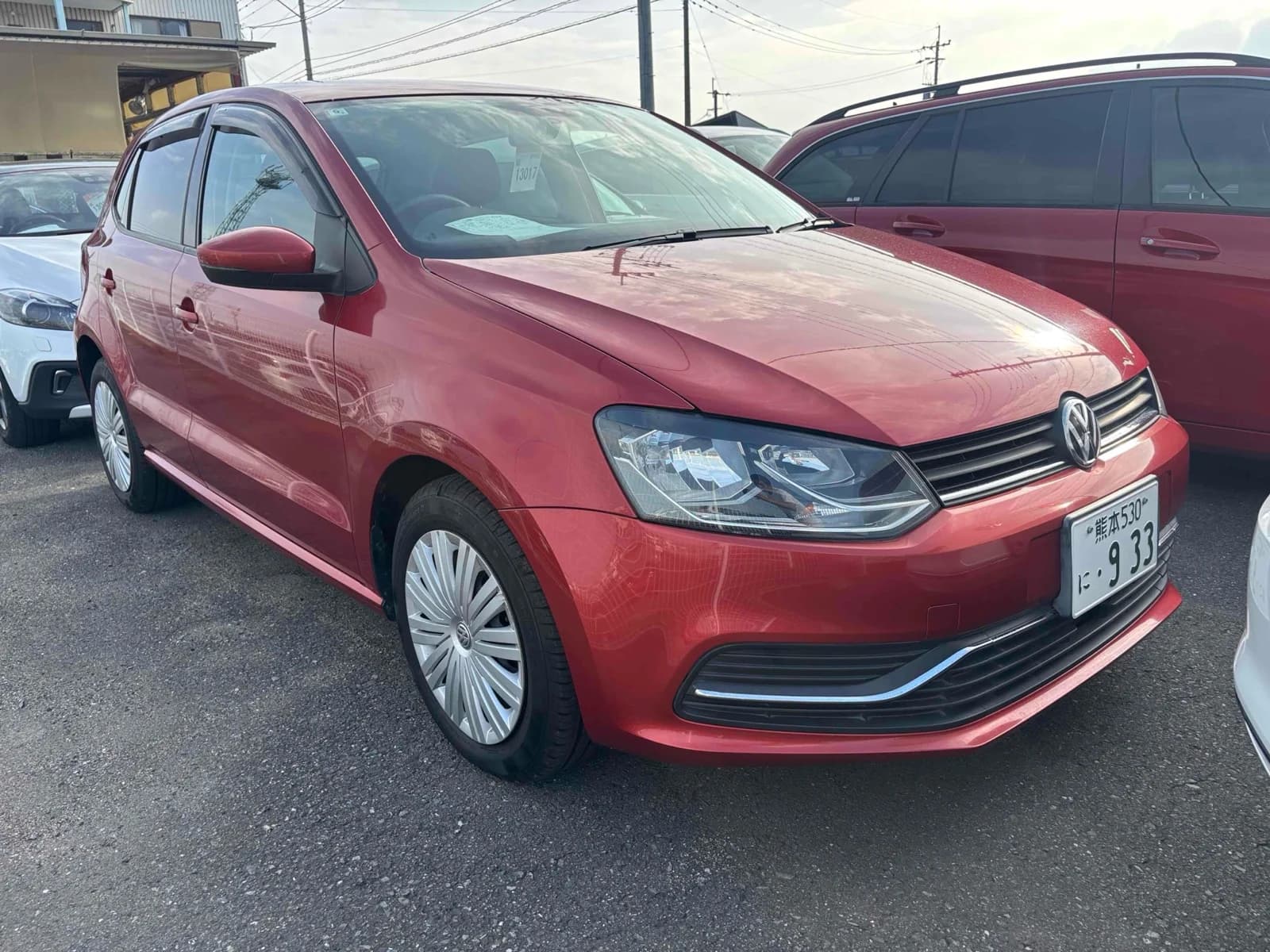 Volkswagen Polo hatchback - Front-right exterior view in an outdoor lot with red metallic paint, LED headlights, and chrome grille