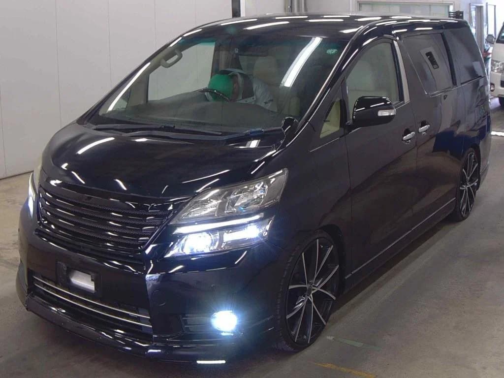 Toyota Alphard Vellfire minivan - Front-left exterior view in black pearl paint with LED headlights, chrome grille, and custom multi-spoke alloy wheels