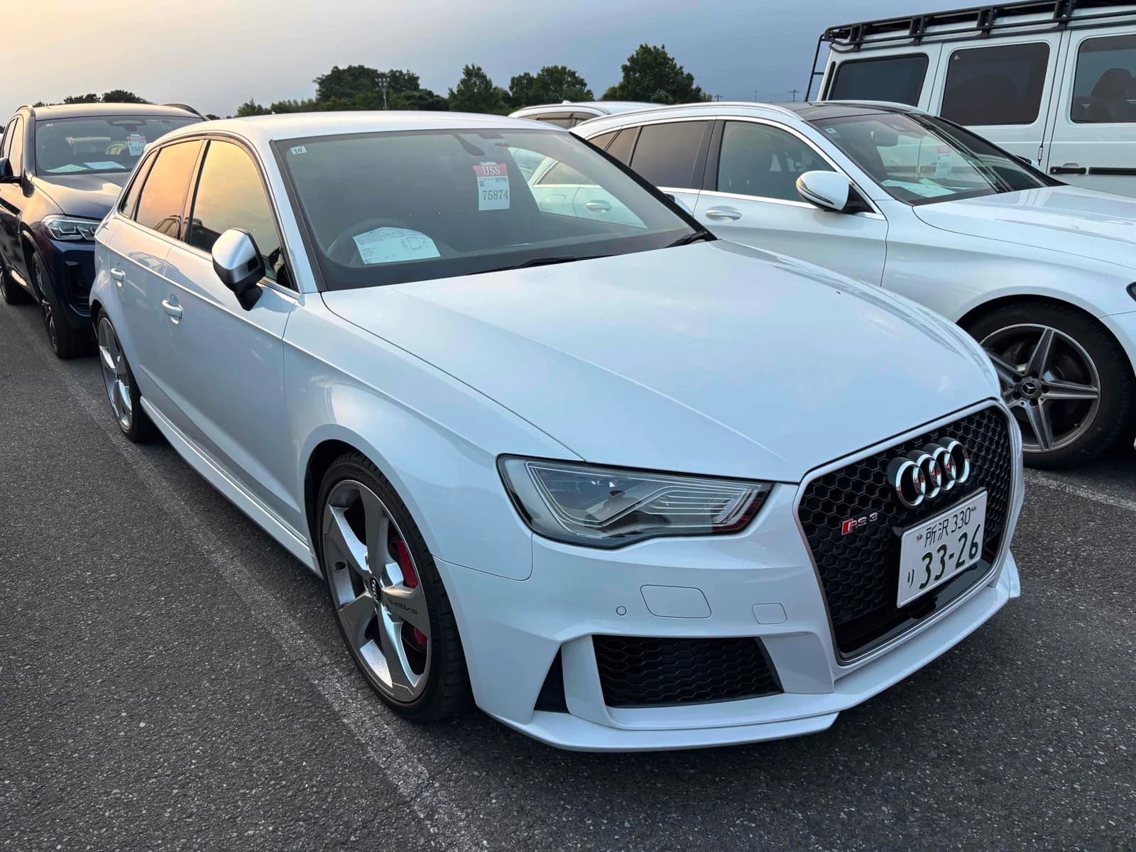 Audi RS3 Sportback - Front-right exterior view with pearl white paint, honeycomb Singleframe grille, quattro badge, and red brake calipers
