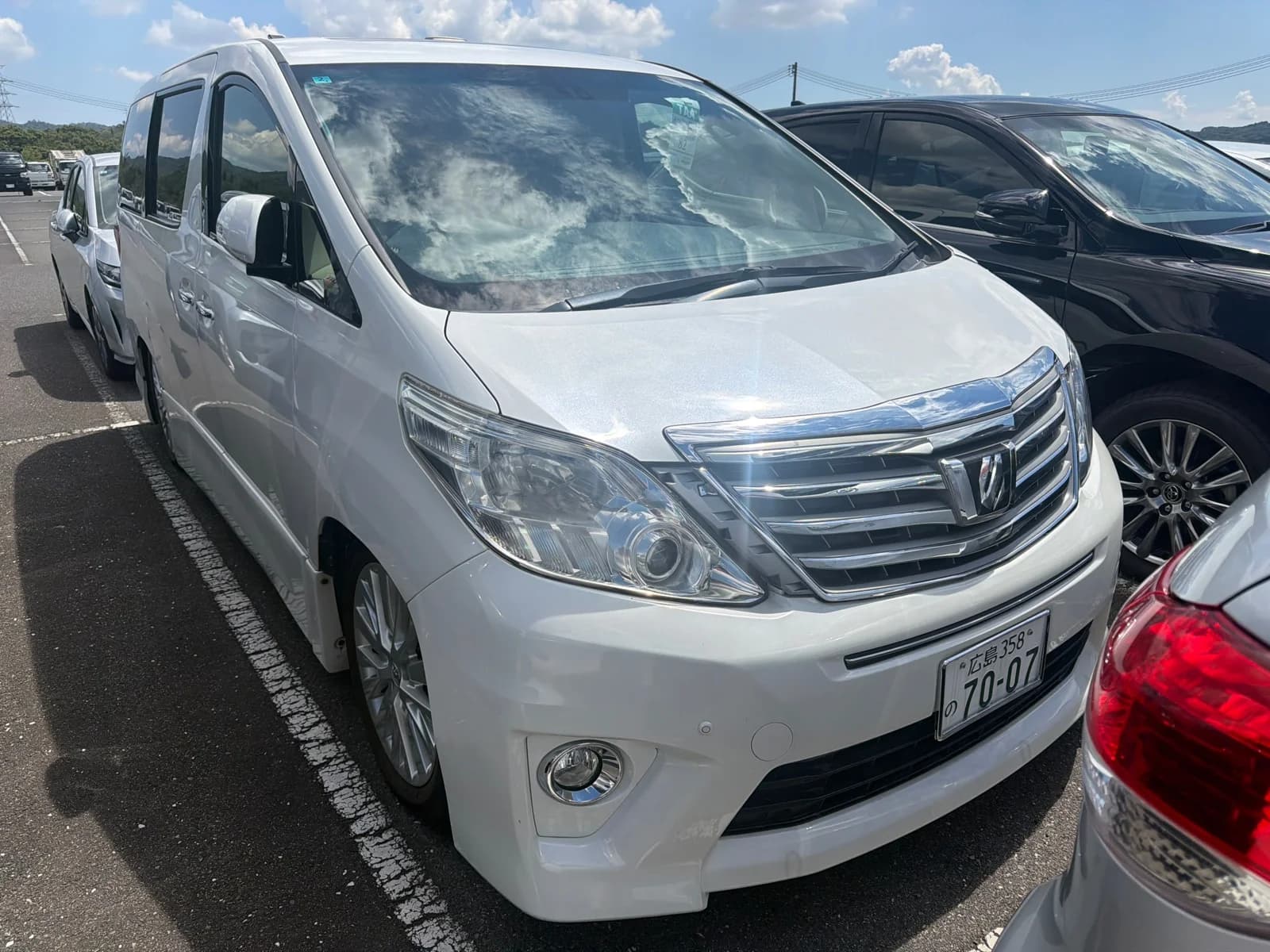 Toyota Alphard minivan - Front-right exterior view with pearl white paint, chrome front grille, projector headlights, and alloy wheels