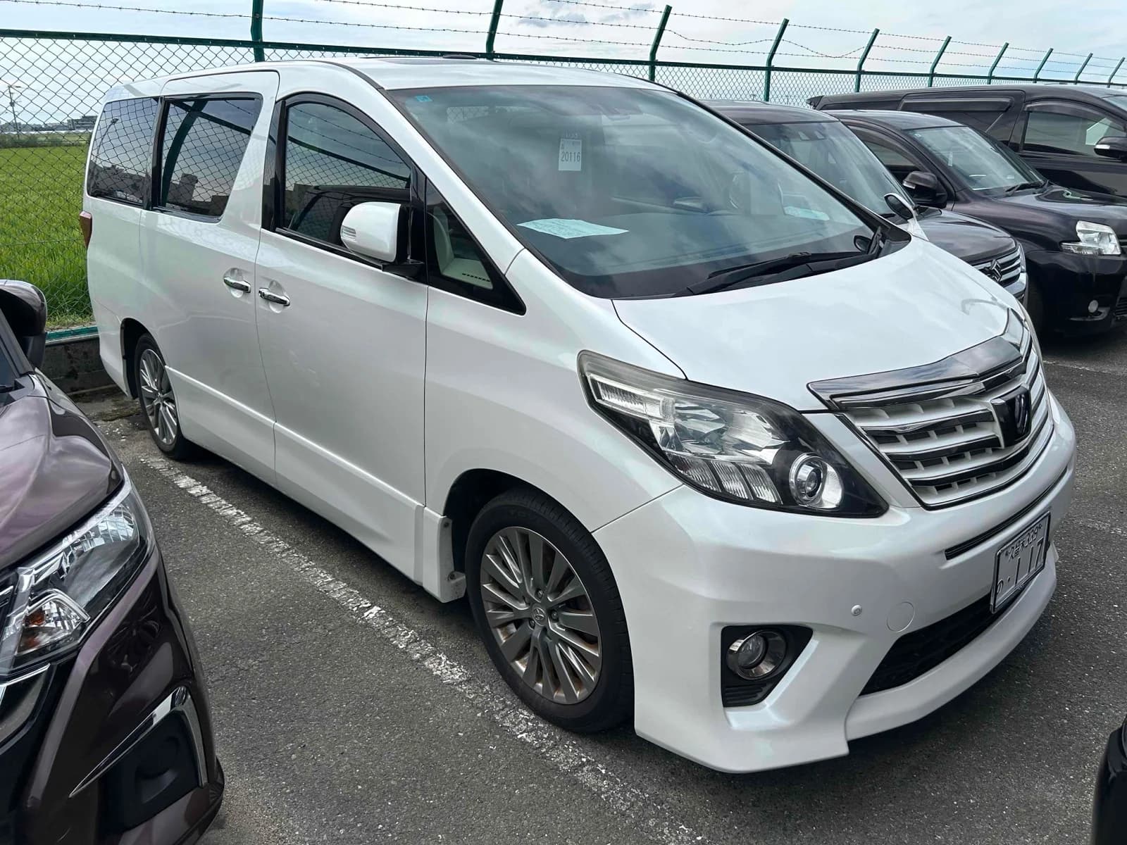 Toyota Alphard minivan - Front-right exterior view with pearl white paint, chrome front grille, LED headlights, and sport alloy wheels