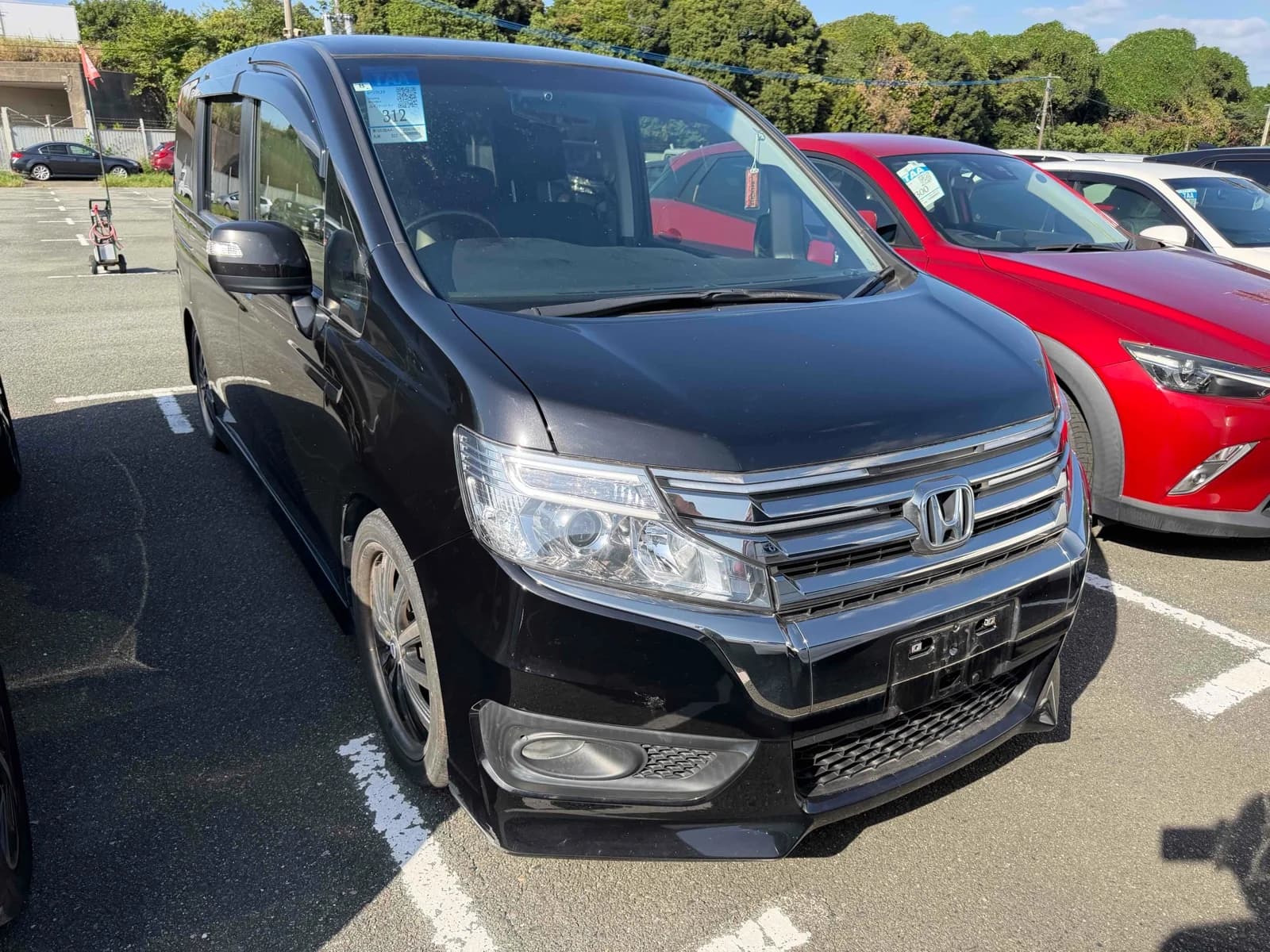 Honda Stepwgn Spada minivan - Front-right exterior view with black paint, chrome wing grille, LED headlights, and alloy wheels