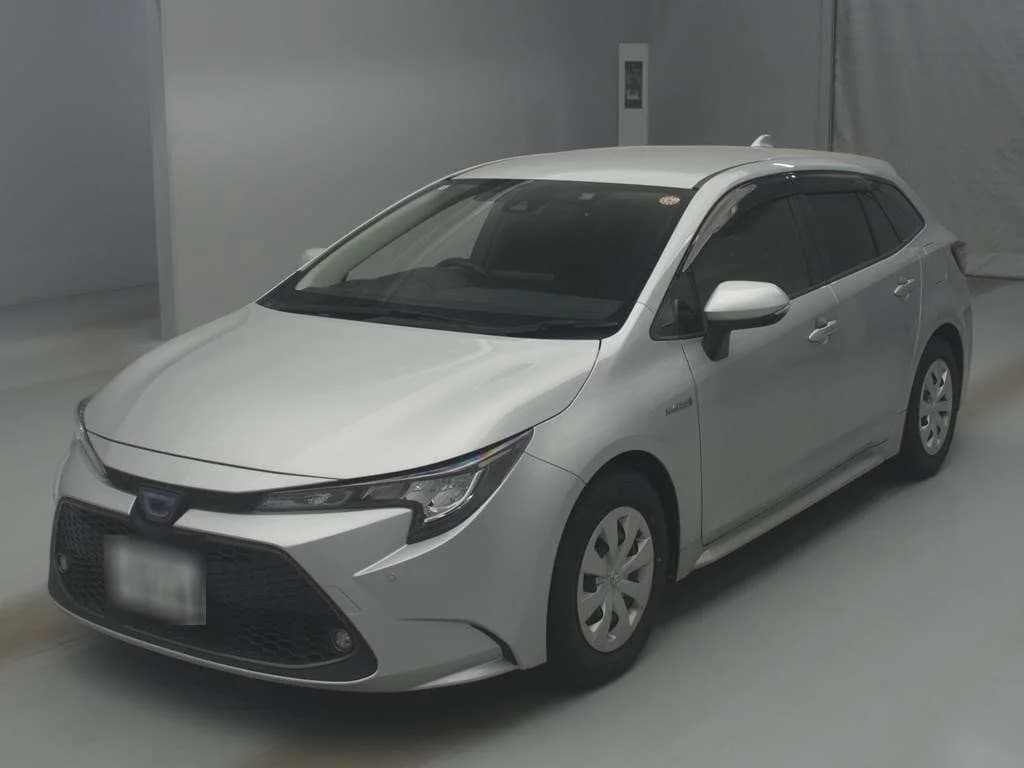 Toyota Corolla Touring wagon - Front-left exterior studio view with silver paint, LED headlights, and hybrid badge