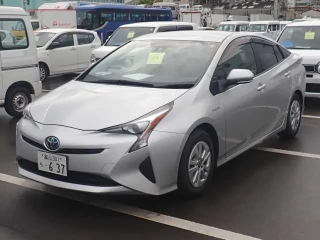 Toyota Prius hatchback - Front-left exterior view with silver paint, LED headlights, and auction tag on windshield at an outdoor lot