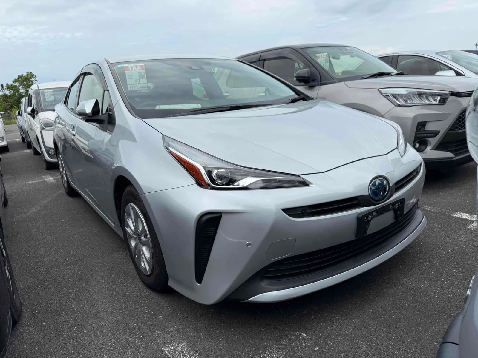 Toyota Prius hatchback - Front-left exterior view with silver paint, LED headlights, and TAA auction tags on windshield