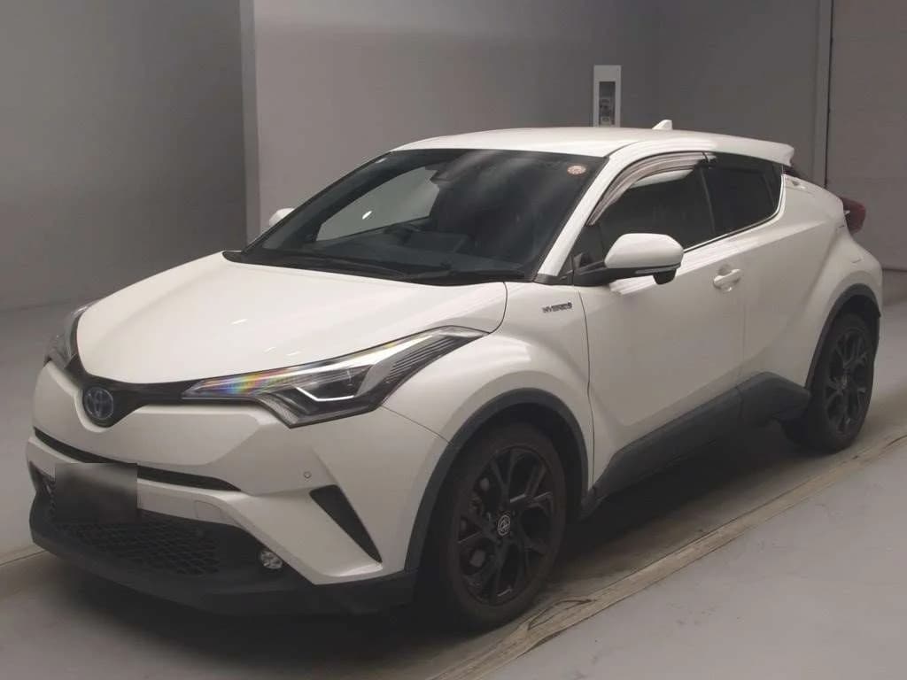 Toyota C-HR Hybrid compact SUV - Front-left three-quarter view in pearl white with LED headlights, hybrid badge, black alloy wheels and gray lower cladding