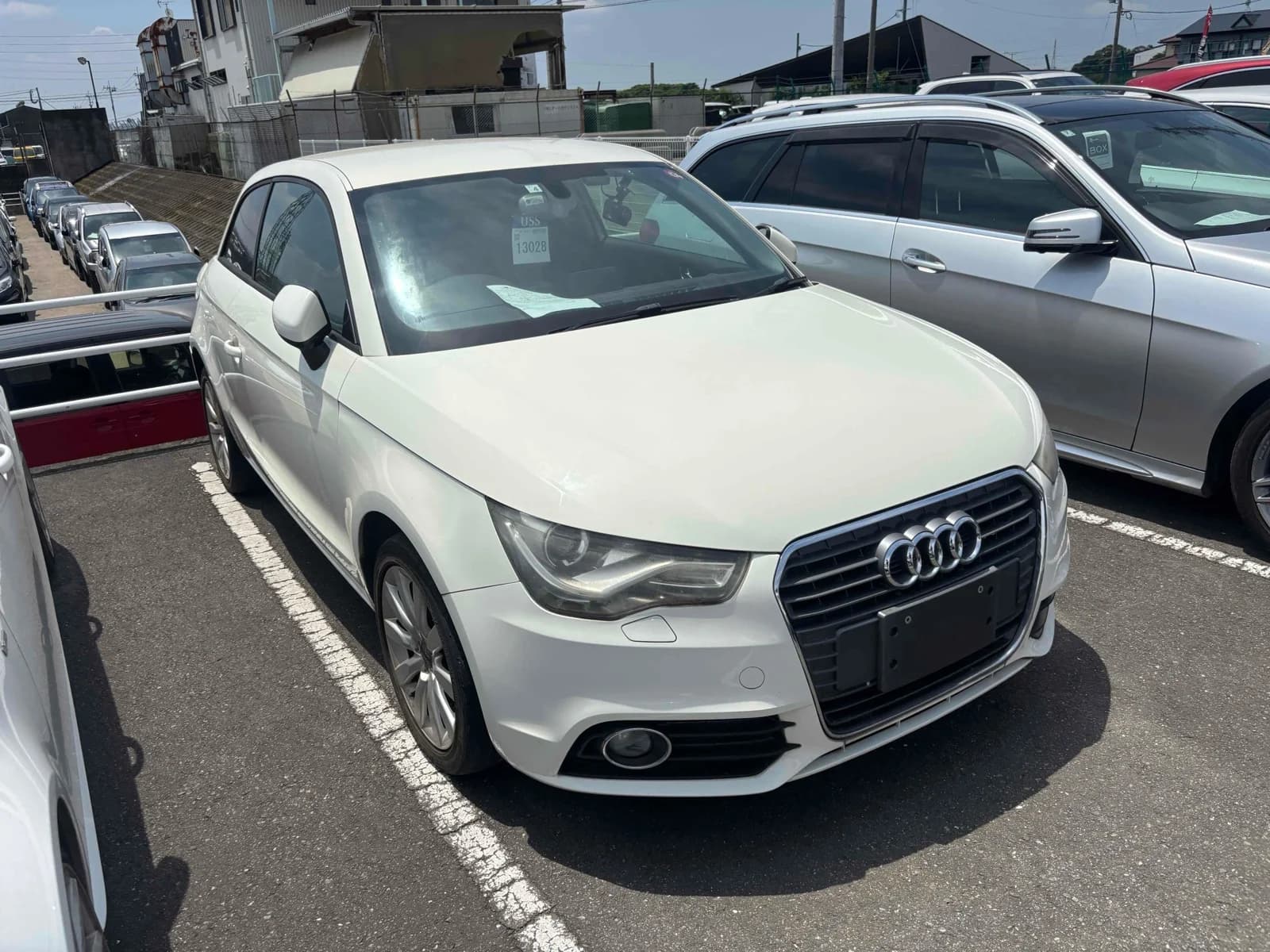 Audi A1 three-door hatchback - Front-right three-quarter view in white with chrome-framed single-frame grille, xenon headlights, fog light and silver alloy wheels