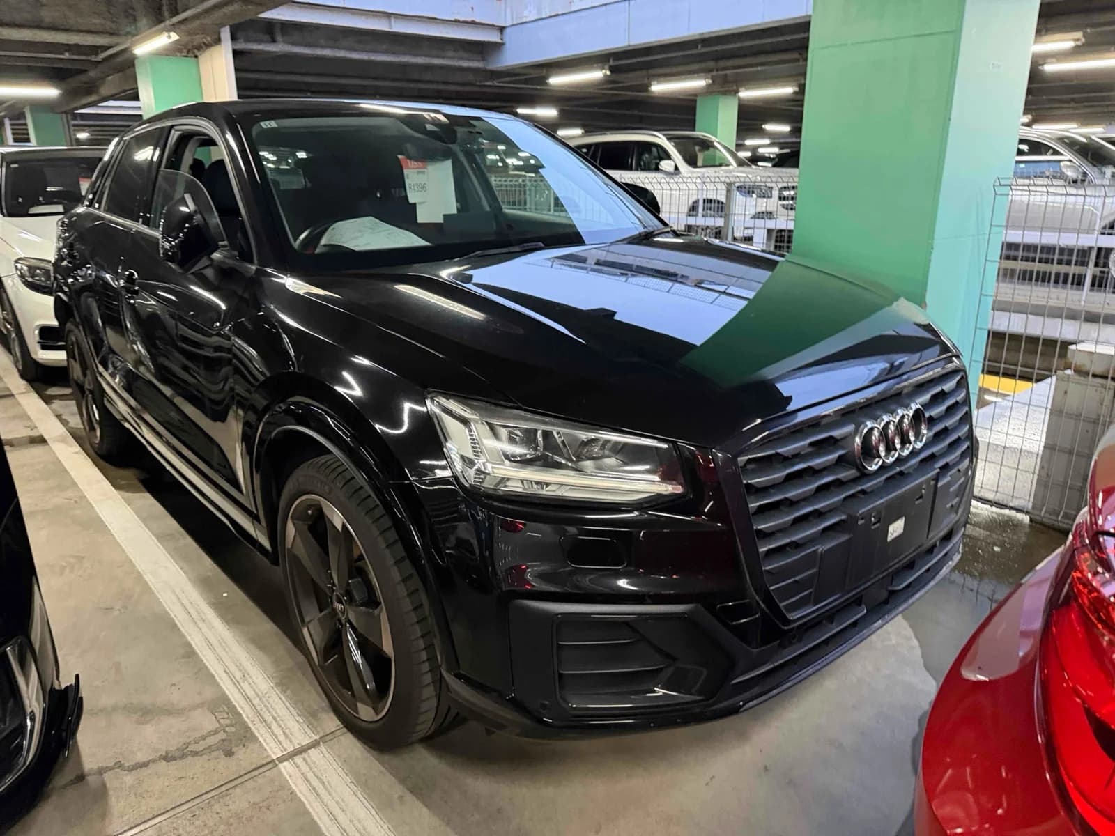 Audi Q2 compact SUV - Front-right three-quarter view in black with large octagonal single-frame grille, LED headlights, black five-spoke alloy wheels and Michelin tires