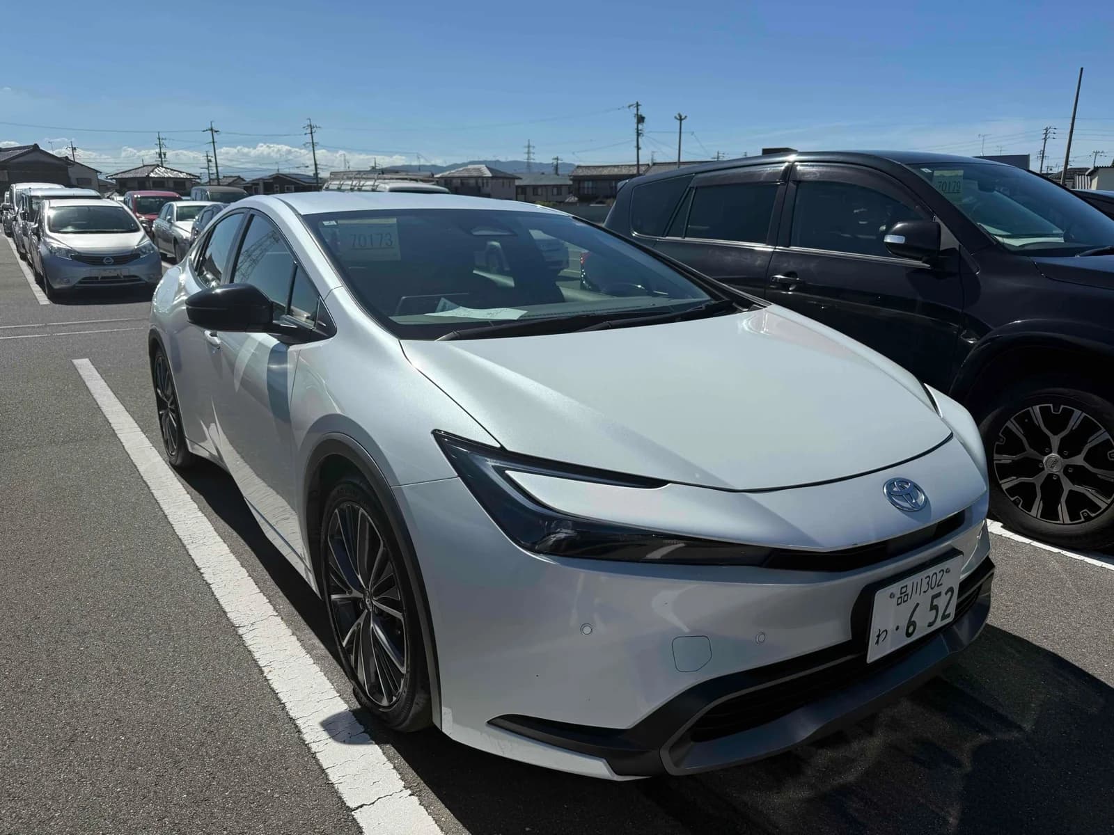 2023 Toyota Prius G hybrid in pearl white - front-right 3/4 view with slim LED headlights, hammerhead front design, and 19-inch alloy wheels