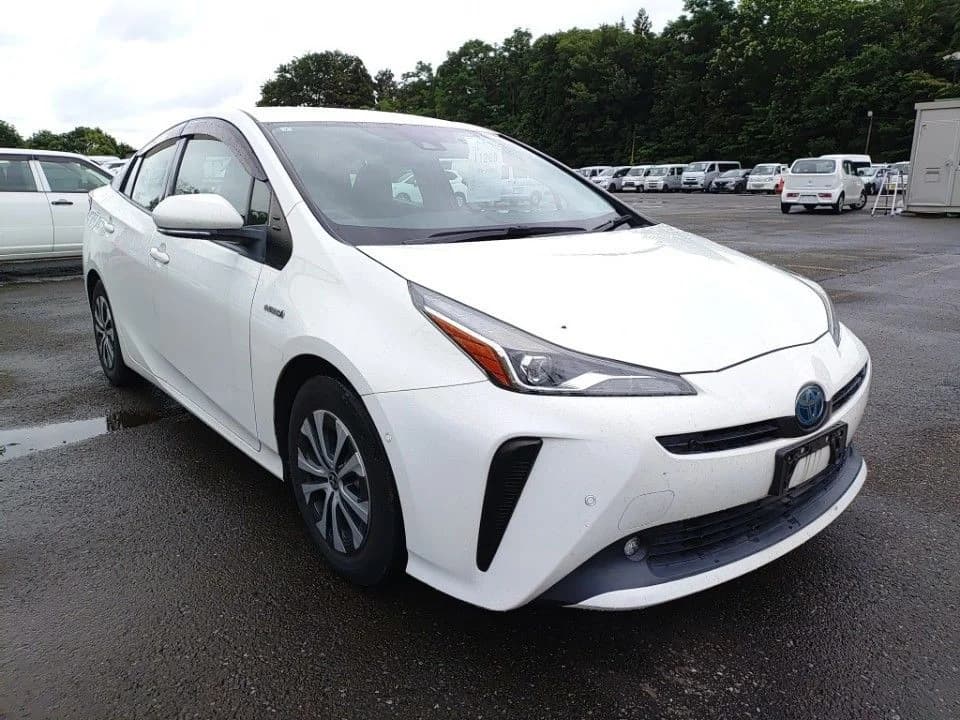 2019 Toyota Prius hybrid in white - front-right 3/4 view with slim LED headlights, vertical bumper accents, window visors, and two-tone wheel covers