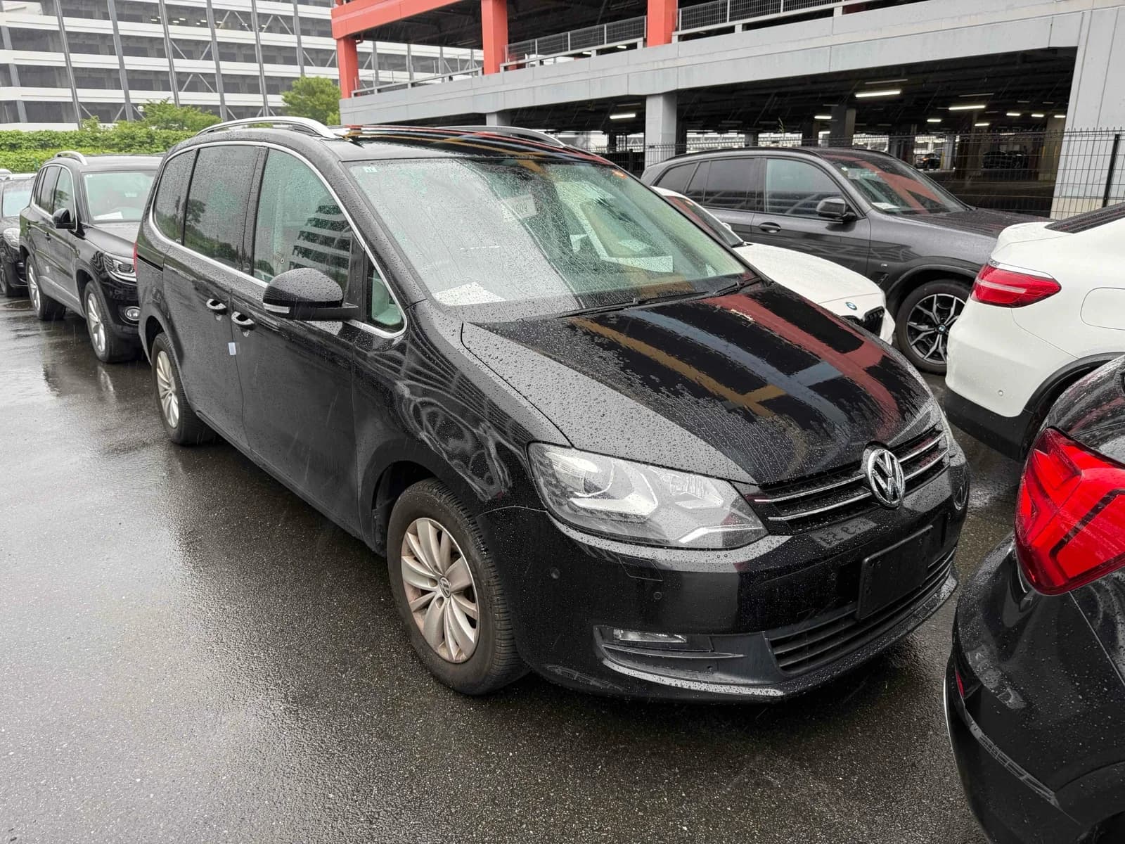 2013 Volkswagen Sharan TSI Comfortline BlueMotion in black - front-right 3/4 view with chrome-trimmed grille, halogen headlights, and silver roof rails