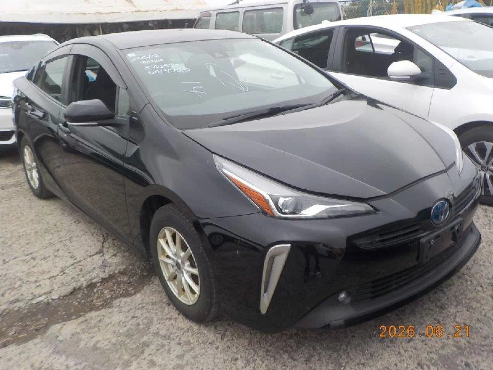 2021 Toyota Prius S Safety Plus II E-Four in black - front-right 3/4 view with LED headlights, chrome vertical bumper accents, window visors, and alloy wheels