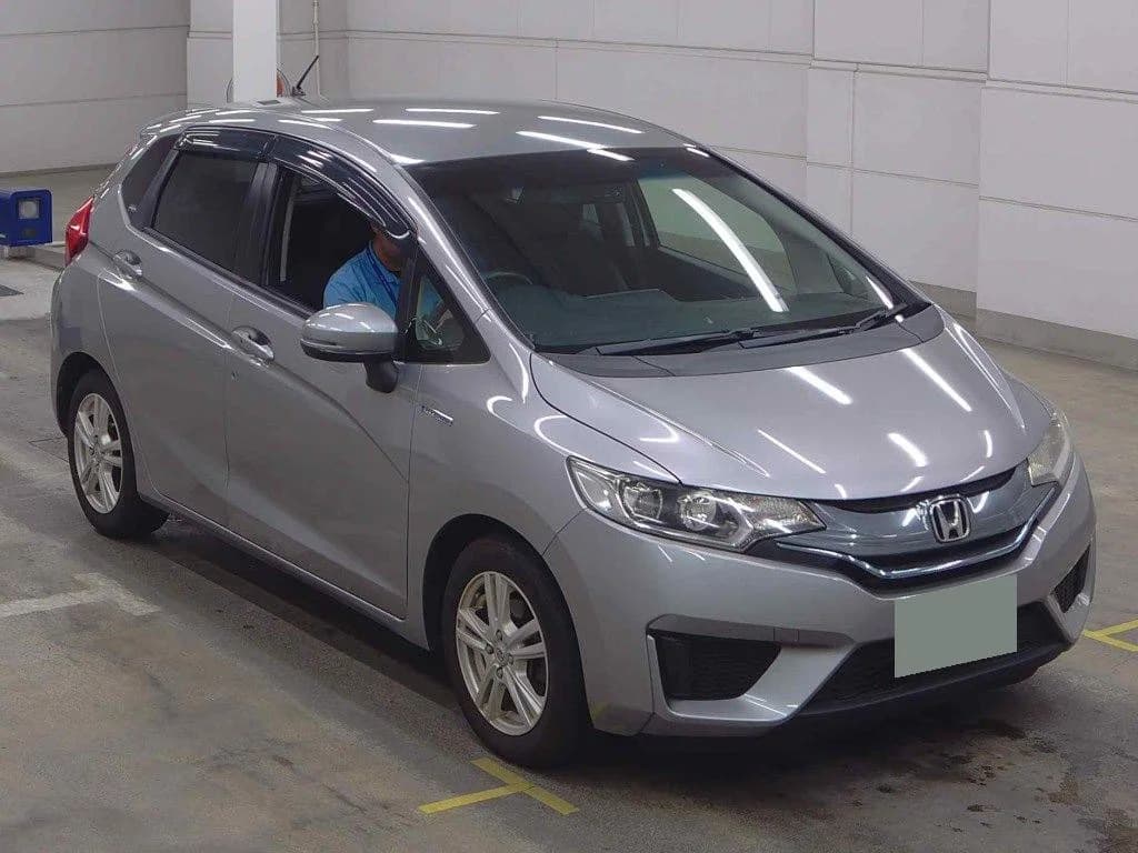 2013 Honda Fit Hybrid L Package in silver metallic - front-right 3/4 view with chrome-accented grille, halogen headlights, window visors, and silver alloy wheels