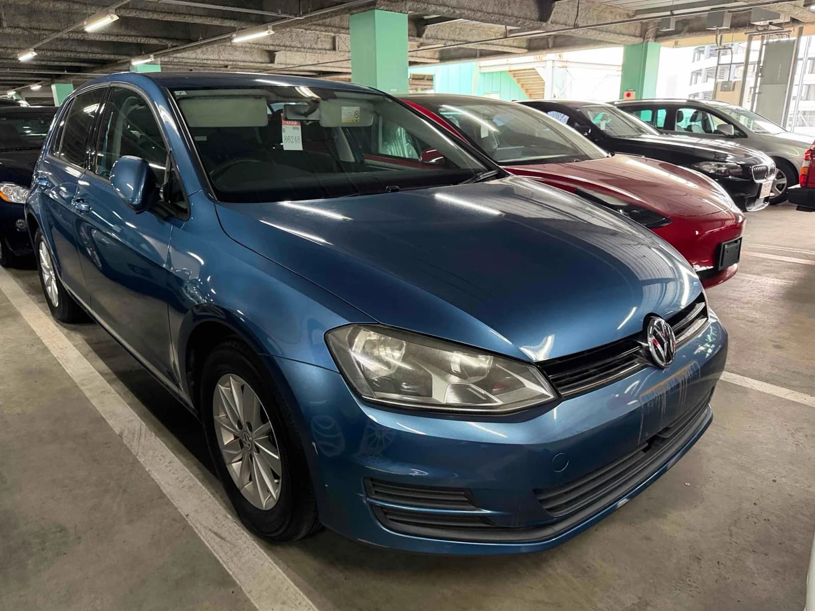Blue Volkswagen Golf hatchback - front three-quarter exterior view with VW emblem, headlights, and silver alloy wheels