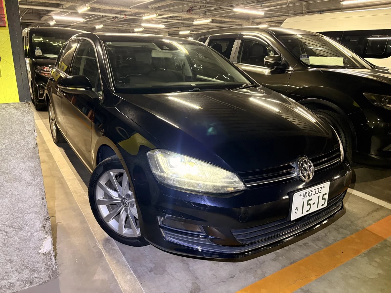 Dark blue-black Volkswagen Golf hatchback - front three-quarter exterior view with VW emblem, headlights, and silver alloy wheels