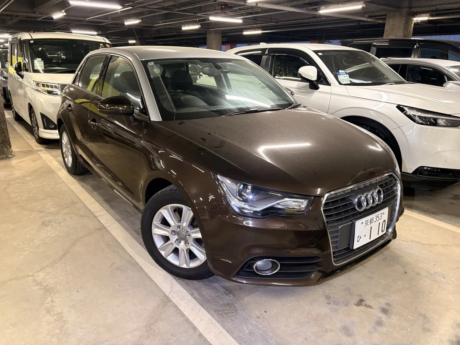 Audi A1 Sportback in brown metallic - front three-quarter exterior view with Audi four-ring grille, headlights, and silver alloy wheels